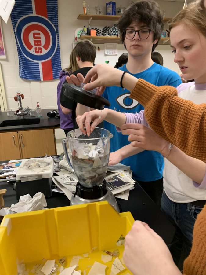 Olivia Wexler (21), co-founder of Earth Club, helps group members create the paper and water mixture.