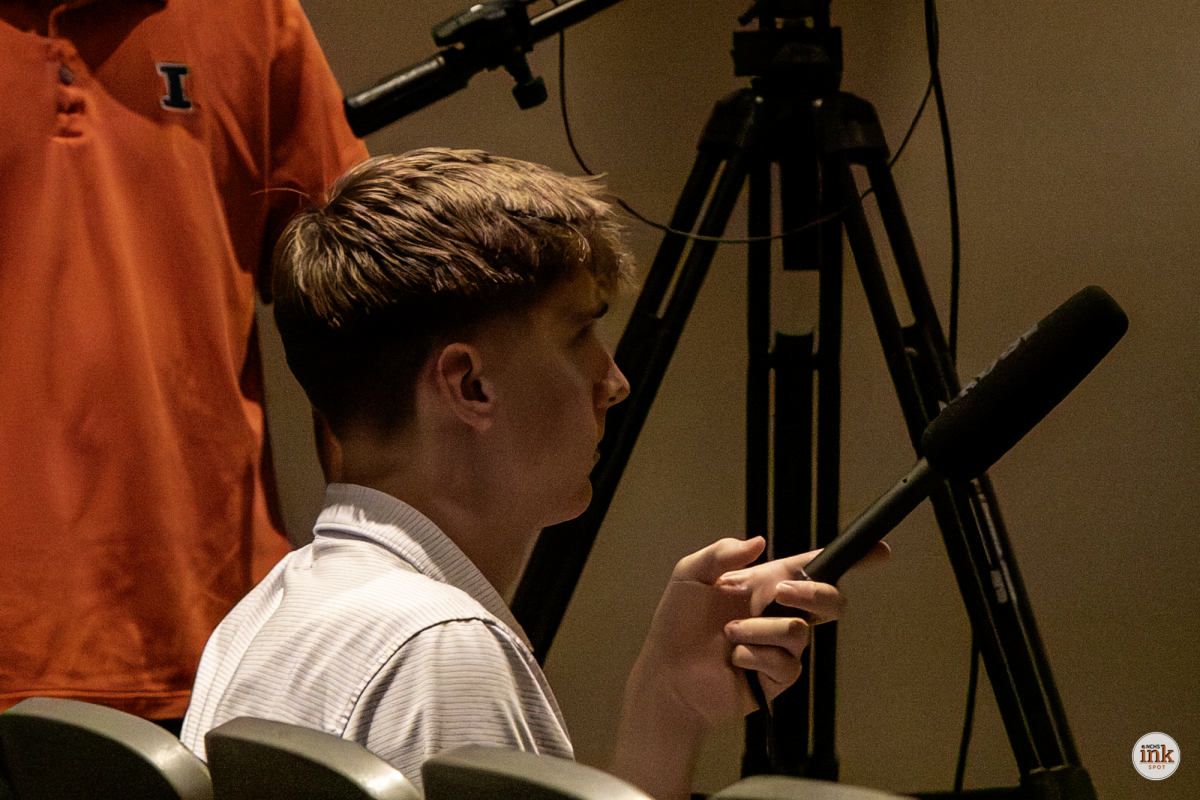 Brady Phelps records audio at a mock debate at Heartland Community College for his second-place Radio News story on the Extemporaneous Debate championship.